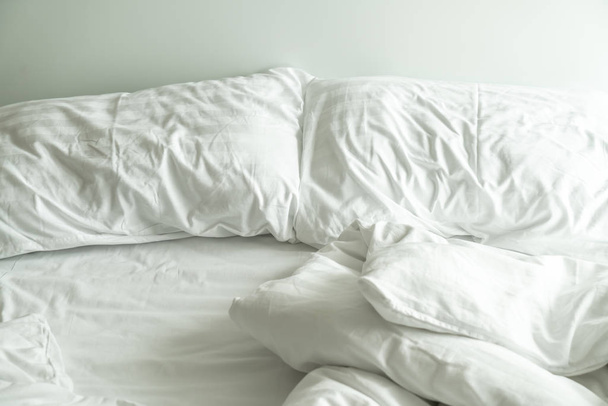 witte hoofdkussen op bed en met de rommelige deken rimpel in slaapkamer - Foto, afbeelding