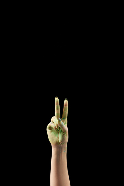 vista ritagliata della donna mostrando gesto di pace in polvere verde holi isolato su nero
 - Foto, immagini