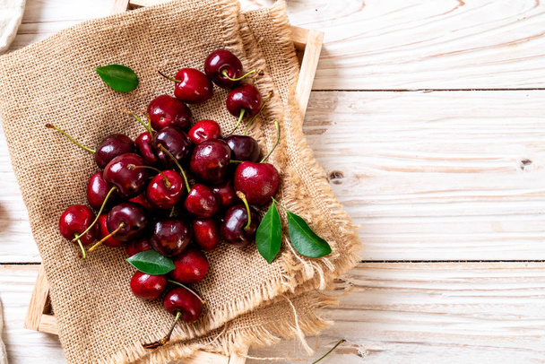 Fresh cherries in bowl  on wood background - Photo, Image