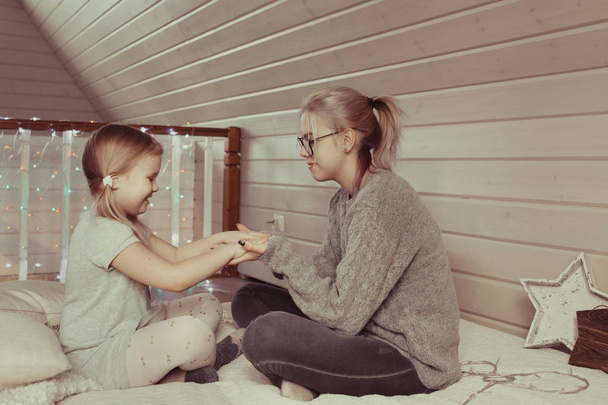 cozy photo session of two beautiful happy sisters in wooden house in style of hyuggi - Foto, Bild