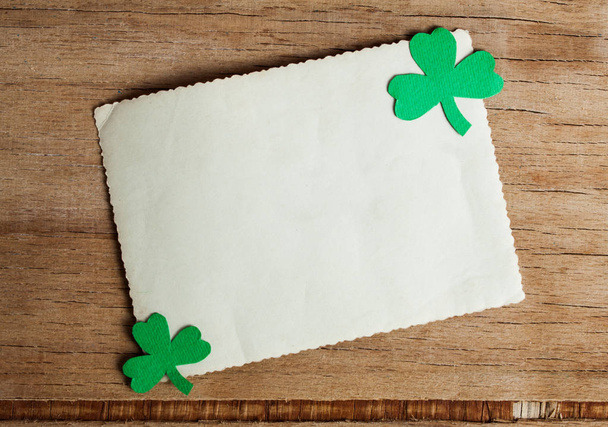 Happy St Patricks Day tag with corner border of shiny shamrocks over a rustic wood background. Place for text - Photo, Image