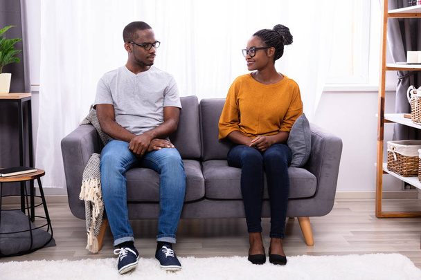 An African Young Couple Sitting On Sofa Looking At Each Other - Foto, Imagem