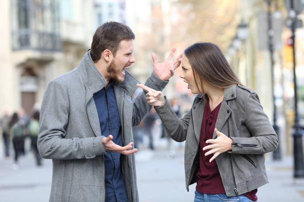 Angry couple arguing in the middle of a city street - Fotoğraf, Görsel
