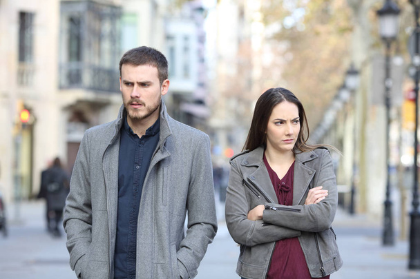 Front view portrait of an angry couple walking in the street after argument - Photo, image