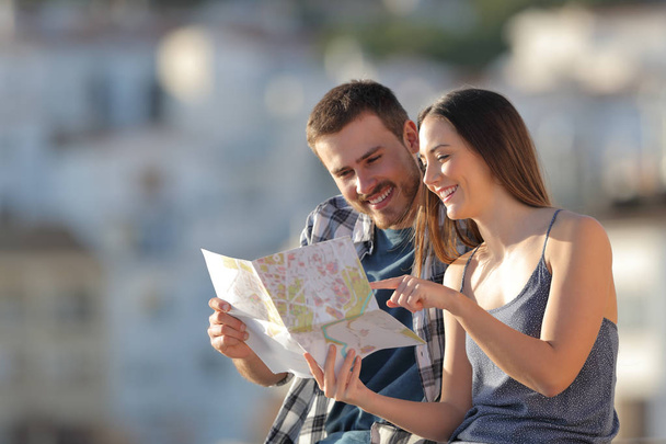Пара счастливых туристов, проверяющих бумажный путеводитель в городе на отдыхе
 - Фото, изображение