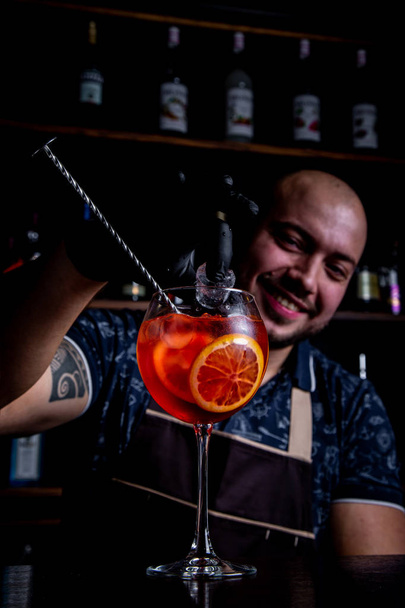 Barman puting to glass of fresh and tasty Aperol syringe cocktail peace of ice - Photo, Image