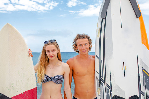 Surfistas en la playa- Pareja sonriente de surfistas caminando por la playa y divirtiéndose en verano. Deporte extremo y concepto de vacaciones
 - Foto, Imagen
