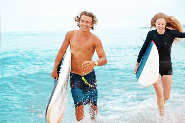 Surfeurs à la plage.Un couple souriant de surfeurs marchant sur la plage et s'amusant en été. Concept de sport extrême et vacances
 - Photo, image