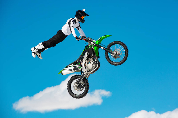 Pilota in moto partecipa a motocross cross-country in volo, salta e decolla sul trampolino di lancio contro il cielo. Concetto riposo estremo attivo
. - Foto, immagini