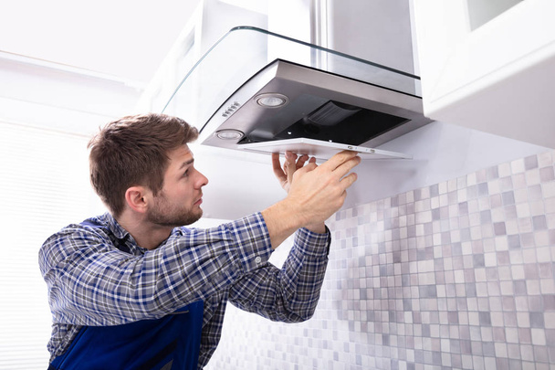 Side View Of Young Male Fixing Kitchen Extractor Filter In Kitchen Room - Photo, Image