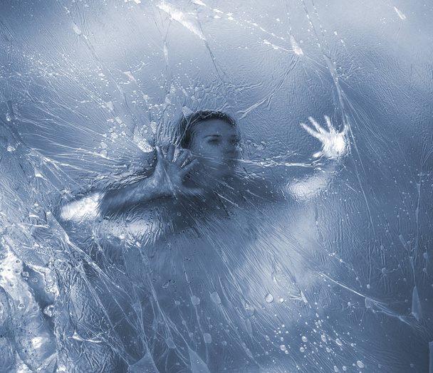 Молодая обнаженная женщина позирует в полиэтиленовой пленке под водой в бассейне
 - Фото, изображение