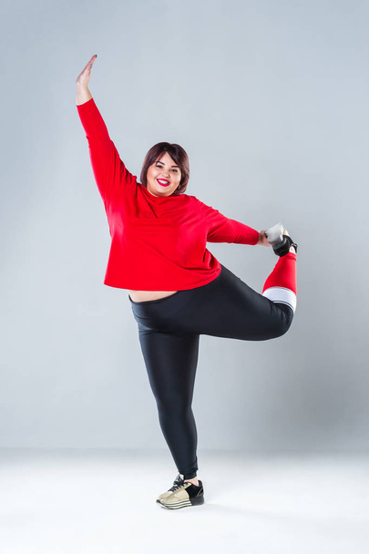 Plus size model in sportswear, fat woman doing workout on gray background, overweight female body, healthy lifestyle concept - 写真・画像
