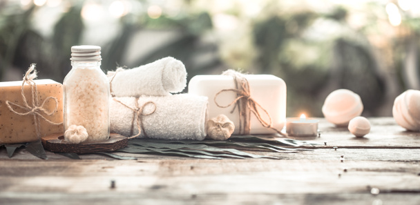 Spa handmade soap with white towels and sea salt, the composition of the tropical leaves with a candle, wooden background with space for text, concept of Spa and relaxation for the body - Photo, Image