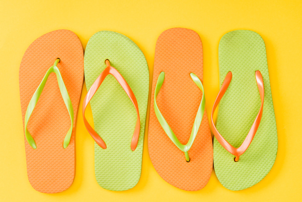top view of colorful flip flops on yellow background  - Foto, immagini