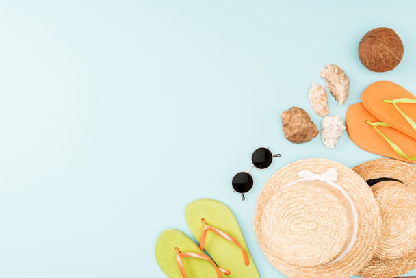 top view of sunglasses, flip flops, straw hats and seashells on blue background  - Photo, Image