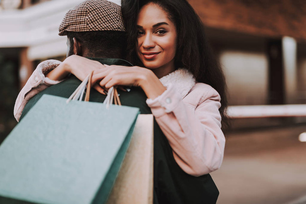 Close up portrait of charming young lady embracing with her beloved male on city background after going shopping together - Photo, image
