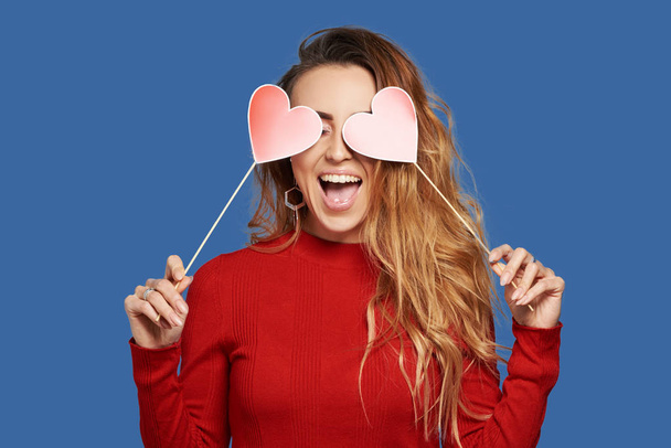 Valentine's Day. Surprised redhair woman with hearts in her hands. Young woman with red hearts on blue background. studio shot with hearts with space for text - Φωτογραφία, εικόνα
