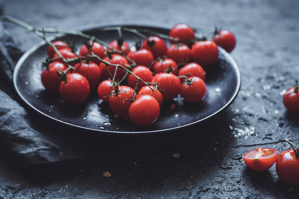 Branch of cherry tomatoes on black plate, close up. Selective focus - Foto, immagini