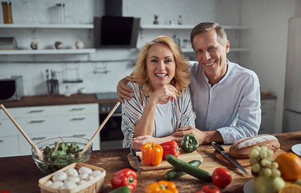 Senior couple is cooking on kitchen. Beautiful woman and handsome man are spending time together at home. Healty lifestyle concept. - Φωτογραφία, εικόνα