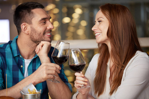 happy couple drinking red wine at restaurant - Zdjęcie, obraz