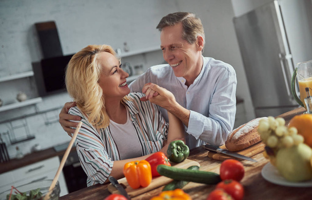 Senior couple is cooking on kitchen. Beautiful woman and handsome man are spending time together at home. Healty lifestyle concept. - Fotografie, Obrázek