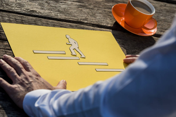 Business vision and success strategy concept - businessman looking at a piece of yellow paper with paper cut businessman climbing up the stairs towards his ambition. - Photo, Image