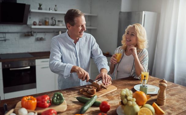 Senior couple is cooking on kitchen. Beautiful woman and handsome man are spending time together at home. Healty lifestyle concept. - Photo, image