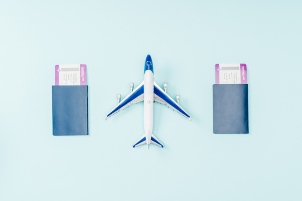 top view of passports, air tickets and toy plane on blue background  - Фото, изображение