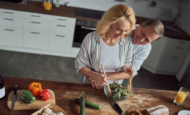 Senior couple is cooking on kitchen. Beautiful woman and handsome man are spending time together at home. Healty lifestyle concept. - Photo, Image