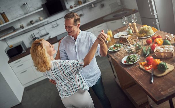 Senior couple is cooking on kitchen. Beautiful woman and handsome man are spending time together at home. Healty lifestyle concept. - Foto, Bild