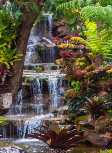 Waterfall flows through cozy home flower garden after rain. - Fotoğraf, Görsel