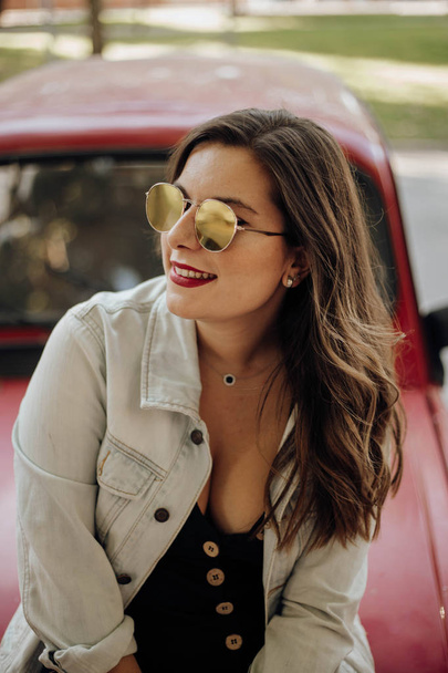 Woman with sunglasses smiling in summer sitting in an old car - Photo, image