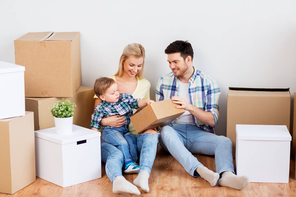 happy family with boxes moving to new home - Foto, Imagem