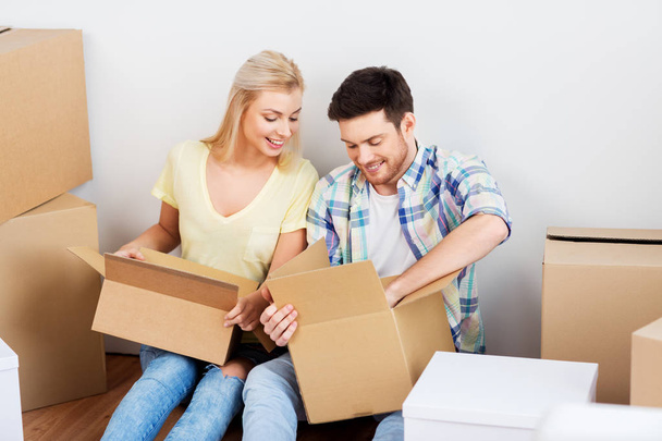happy couple unpacking boxes at new home - Foto, Imagem