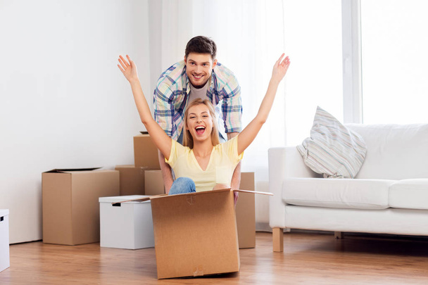 happy couple having fun with boxes at new home - 写真・画像