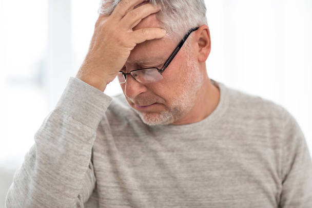 Hombre mayor que sufre de dolor de cabeza en casa
 - Foto, imagen