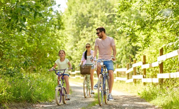 happy family riding bicycles in summer park - Fotó, kép