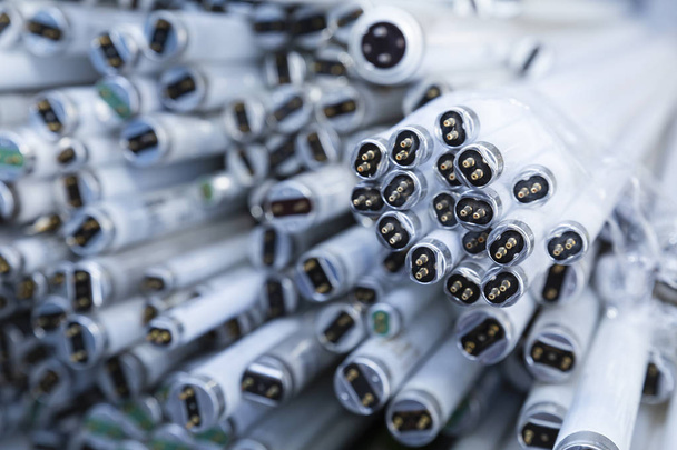 Primer plano de una pila de tubos de lámparas de neón en desuso y desechados que esperan ser reciclados
 - Foto, imagen