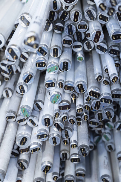 Primer plano de una pila de tubos de lámparas de neón en desuso y desechados que esperan ser reciclados
 - Foto, imagen