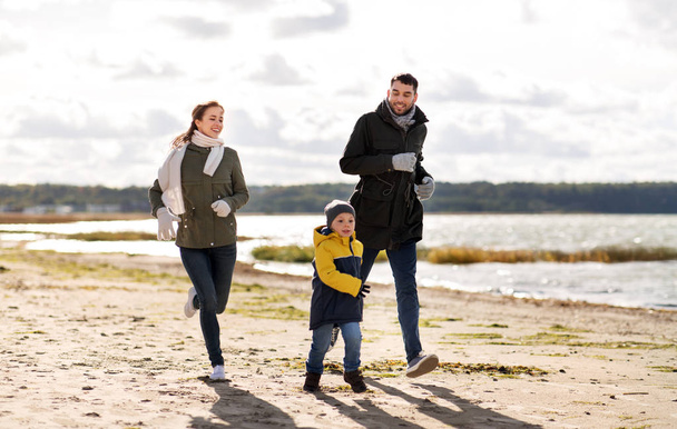 happy family running along autumn beach - Fotó, kép