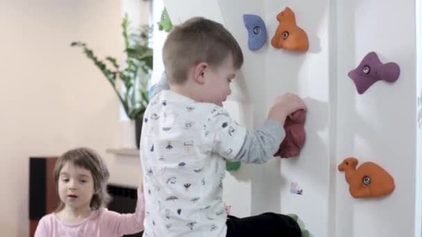 Cute little child trains on the climbing wall indoor - Filmmaterial, Video