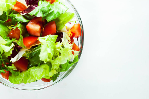 различные свежие листья салата с помидорами в стеклянной чаше изолированы на белом фоне
. - Фото, изображение