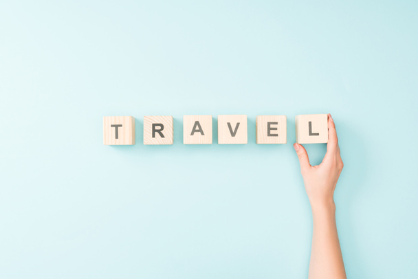 cropped view of woman and wooden cubes with travel lettering on blue background - Фото, изображение