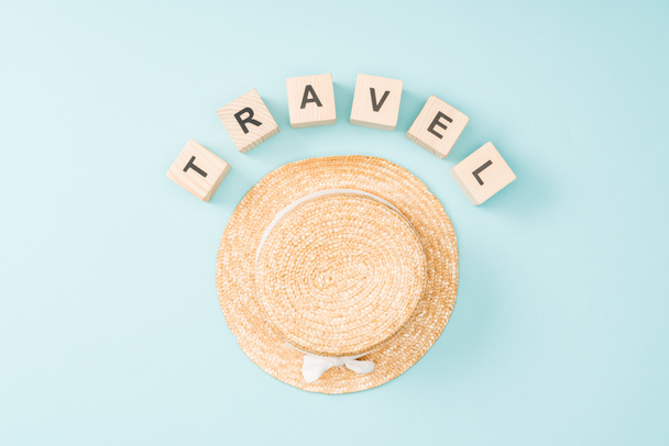pohled shora dřevěných kostek s nápisy cestování a slaměný klobouk na modrém pozadí - Fotografie, Obrázek