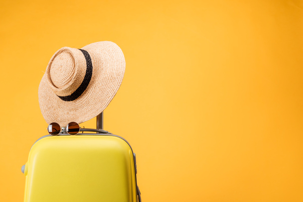 utazótáska, szalma kalap és napszemüveg, elszigetelt, a sárga - Fotó, kép