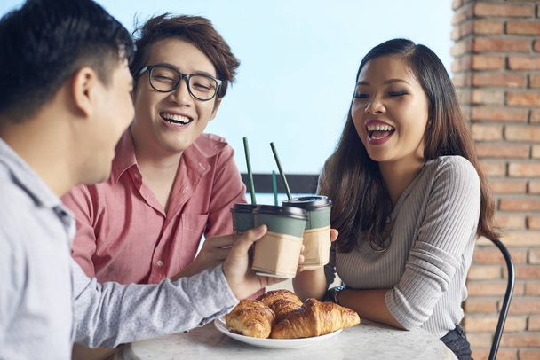 Young happy Asian woman and men toasting with coffee cup having fun on break - Фото, зображення