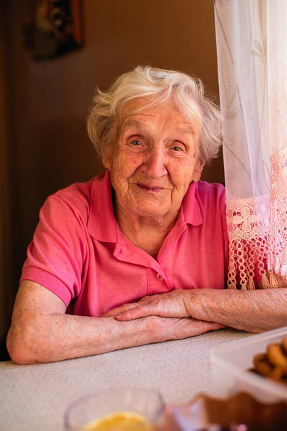 Bejaarde oma drinkt thee in haar huis. Portret. - Foto, afbeelding