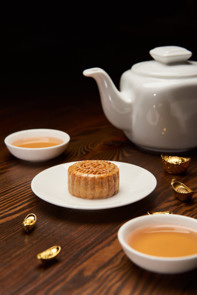 traditional mooncake with tea cups, pot and gold ingots isolated on black - Photo, Image