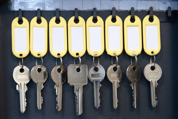 Colgar las llaves en el armario de metal para la oficina de seguridad o la gestión y mantenimiento de las llaves del hogar. llaves con etiquetas de nombre en blanco, espacio para texto
 - Foto, imagen