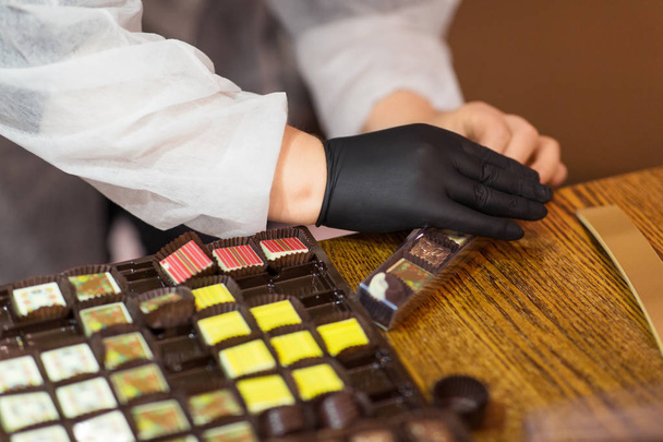 sweets production and industry concept - confectioner or worker packing candies at confectionery shop - Zdjęcie, obraz